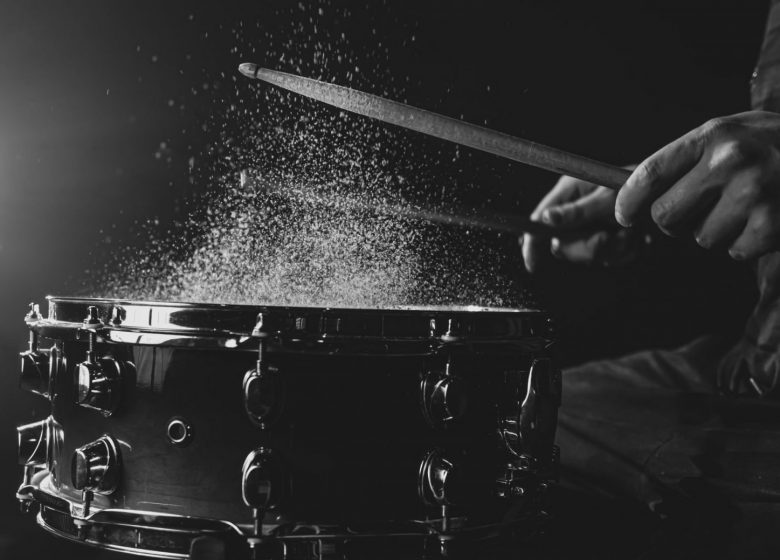 drum-sticks-hitting-snare-drum-with-splashing-water-black-background-stage-lighting